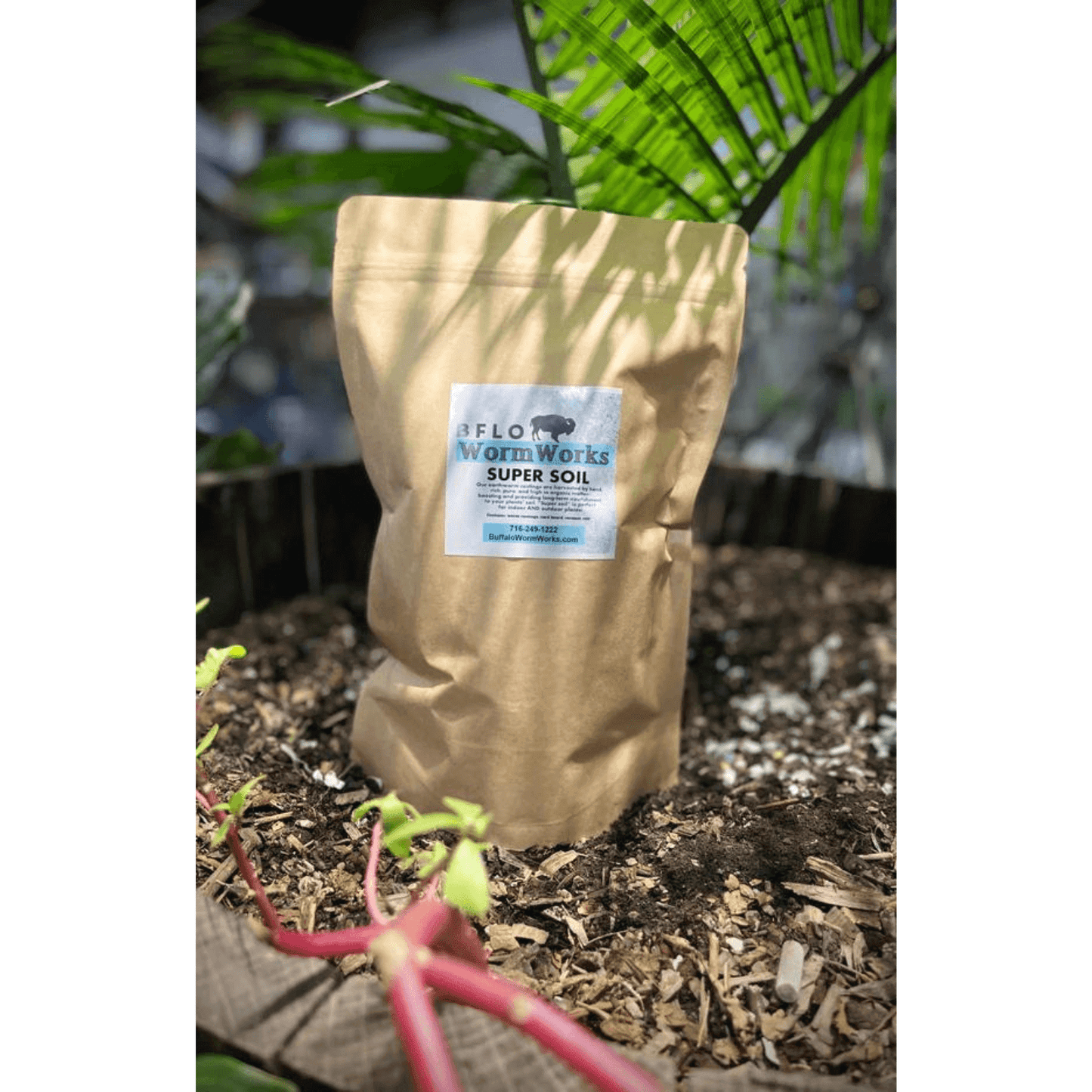 BFLO Worm Works Worm Castings bag in garden, eco-friendly organic soil enhancer for plant nourishment and waste reduction.