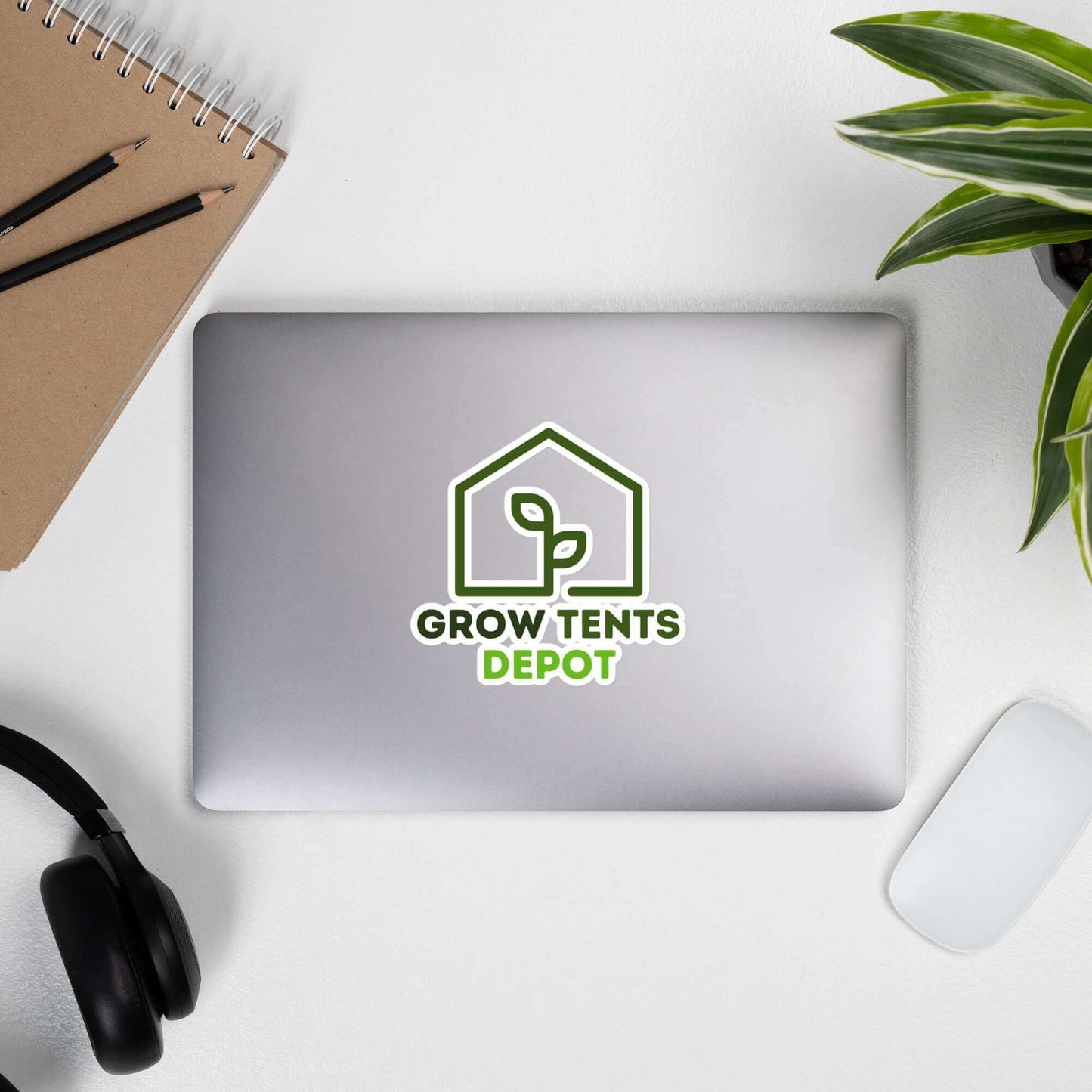 Grow Tents Depot bubble-free sticker on a laptop, surrounded by a notebook, headphones, and a plant.